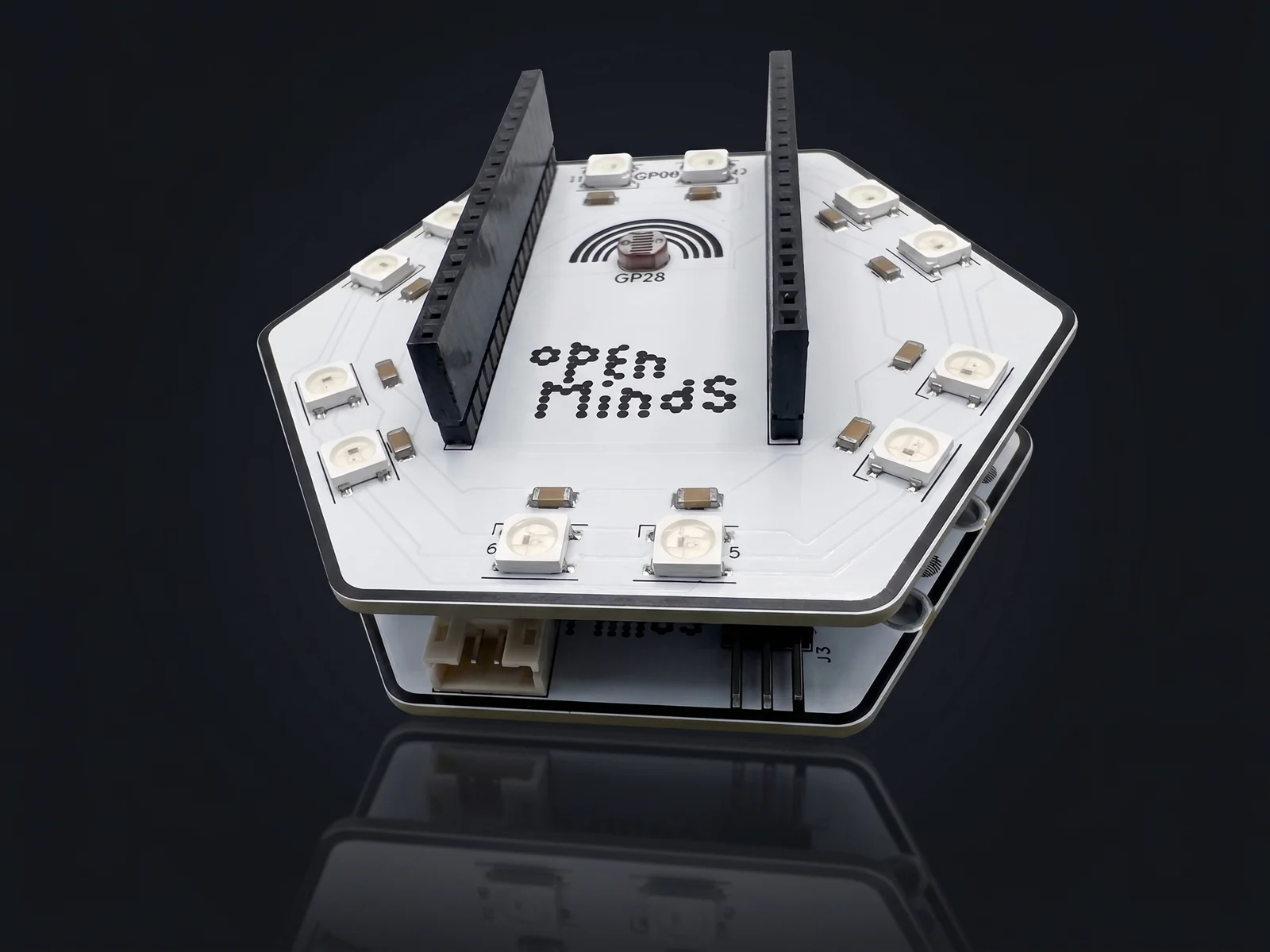 The Open Minds hexagonal microboard with a Light and Colour sensor hat stacked on top, a ring of addressable LEDs around the dot-matrix Open Minds logo.